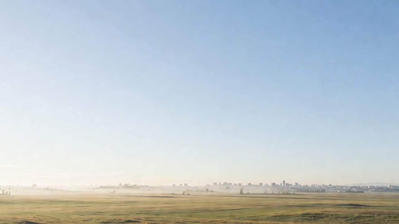 A wide bright morning sky over an open, calm landscape